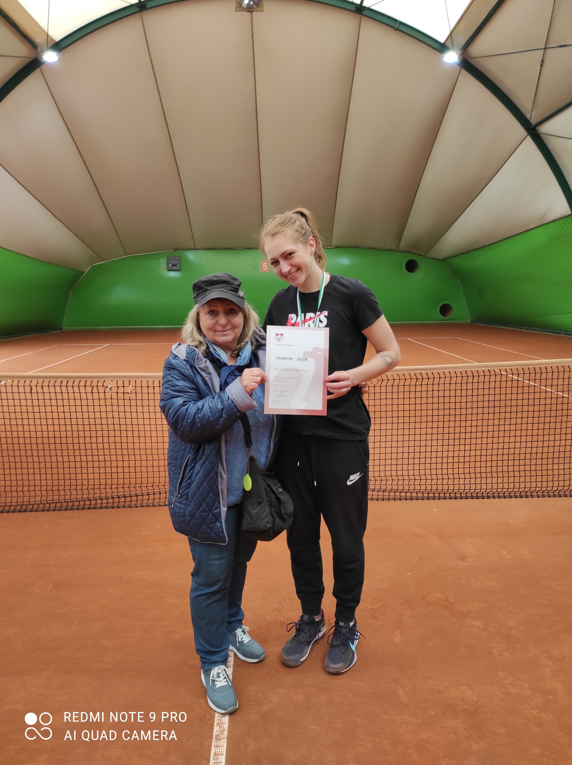 Zdjęcie przedstawia dwójkę kobiet na korcie tenisowym