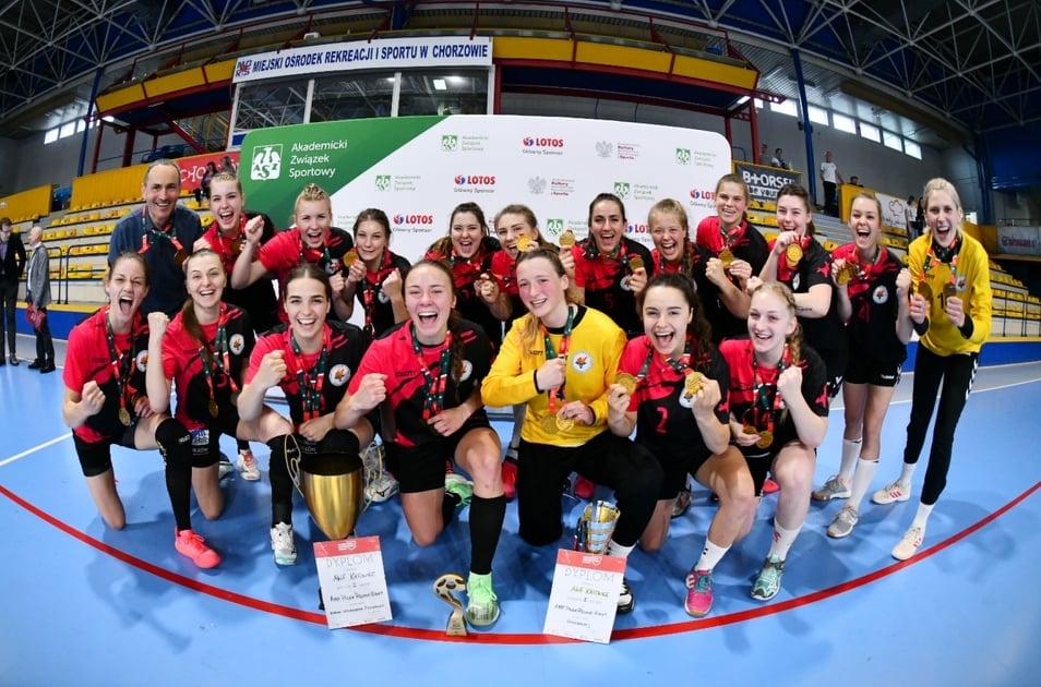 Zdjęcie przedstawia grupę ludzi uśmiechających się trzymając medale