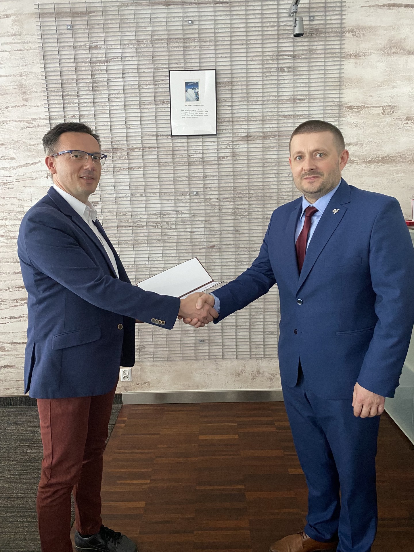 Zdjęcie przedstawia dwójkę mężczyzn ściskających sobie ręce