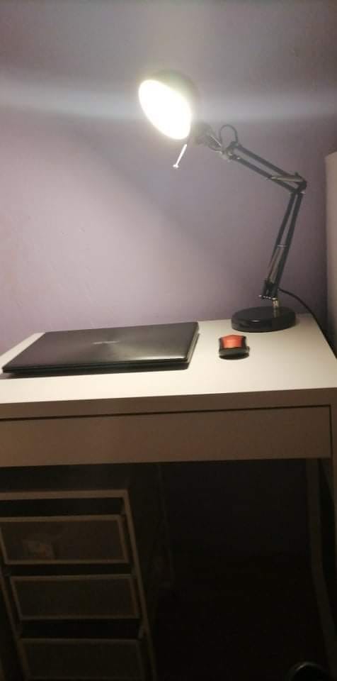 Zdjęcie biurka na którym znajduje się laptop i lampka nocna