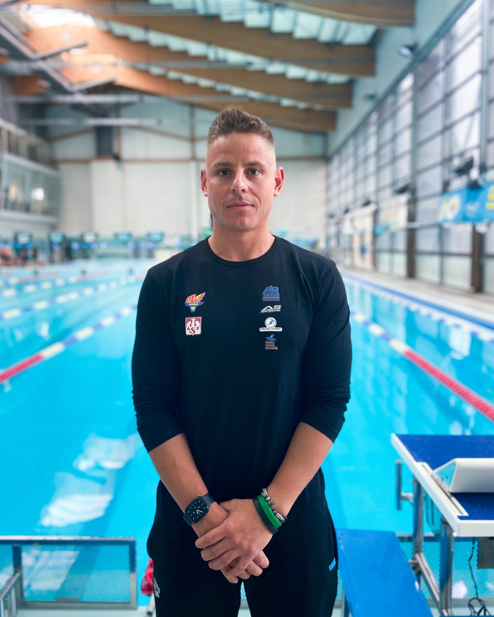 Zdjęcie przedstawia mężczyznę stojącym przy basenie