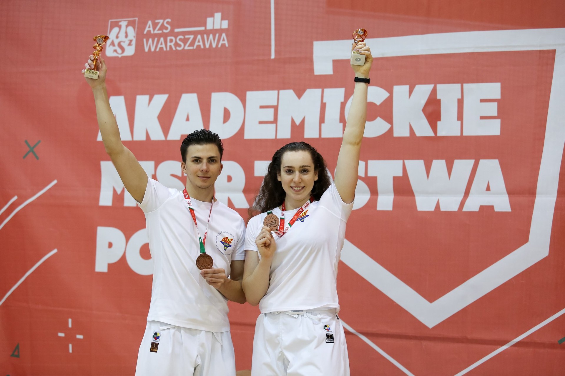 Zdjęcie przedstawia mężczyznę i kobietę trzymających medale